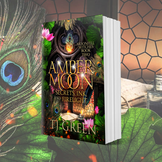 Book titled 'Amber Moon: Secrets, Ink and Firelight' by T.J. Green with a peacock feather and leaves in the background. Paranormal Witch Fiction Dual Timeline Fantasy