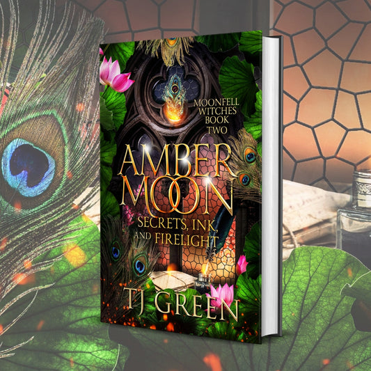 Book titled 'Amber Moon' by T.J. Green with decorative elements like peacock feathers and flowers. Paranormal Witch Fiction, mystery, urban fantasy, dual timeline historical .