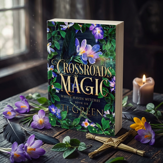 Book titled 'Crossroads Magic' by Ti Green on a wooden surface with flowers and a candle.
