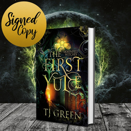 Book titled 'The First I Yule' by TJ Green with a fantasy cover design on a wooden surface. Paranormal Witch Fiction