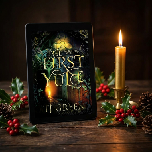 Book titled 'The First Yule' by TJ Green with a candle and holly on a wooden surface